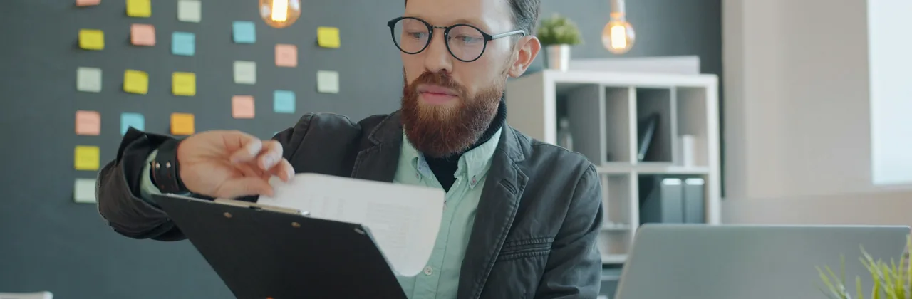 Un homme &agrave; lunettes lisant un document &agrave; son bureau