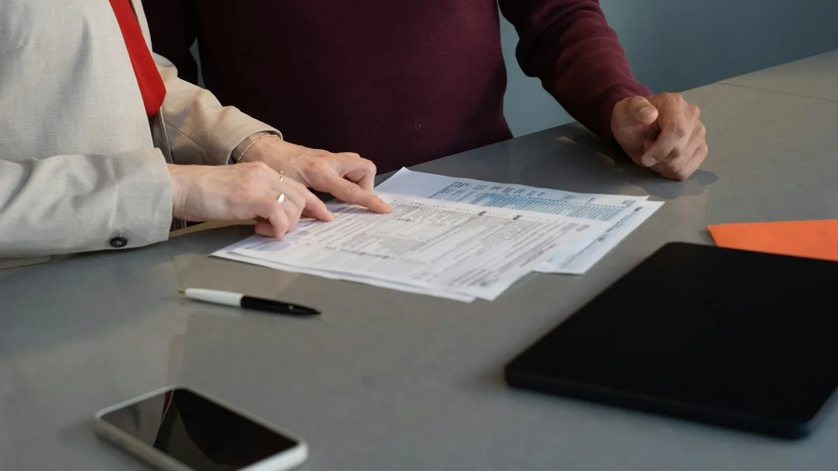Deux personnes remplissant un formulaire papier &agrave; une table
